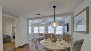 A dining area with a round table, wicker chairs, and a hanging light fixture.