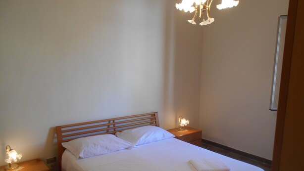 A neatly made bed with white linens, two bedside tables with lamps, and a chandelier above the bed. - Dependance "L Antica Locanda" (Reggio Calabria)