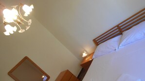 A bedroom with a wooden headboard, a bedside table with a lamp, a mirror, and a neatly made bed with white linens. - Dependance "L Antica Locanda" (Reggio Calabria)