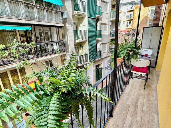 A balcony with potted plants and a table with chairs.
