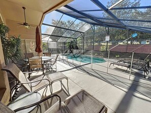Une véranda avec une piscine, des chaises et un ventilateur de plafond.