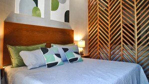 A neatly made bed with a wooden headboard, two abstract paintings on the wall, and a chevron-patterned wooden panel. - Tulum Swim Up Estudio Selvático (Tulum)