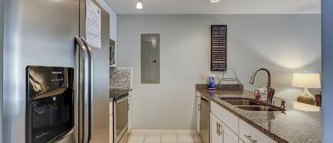 A modern kitchen with a refrigerator, oven, and sink. There is a sign on the wall listing famous landmarks.
