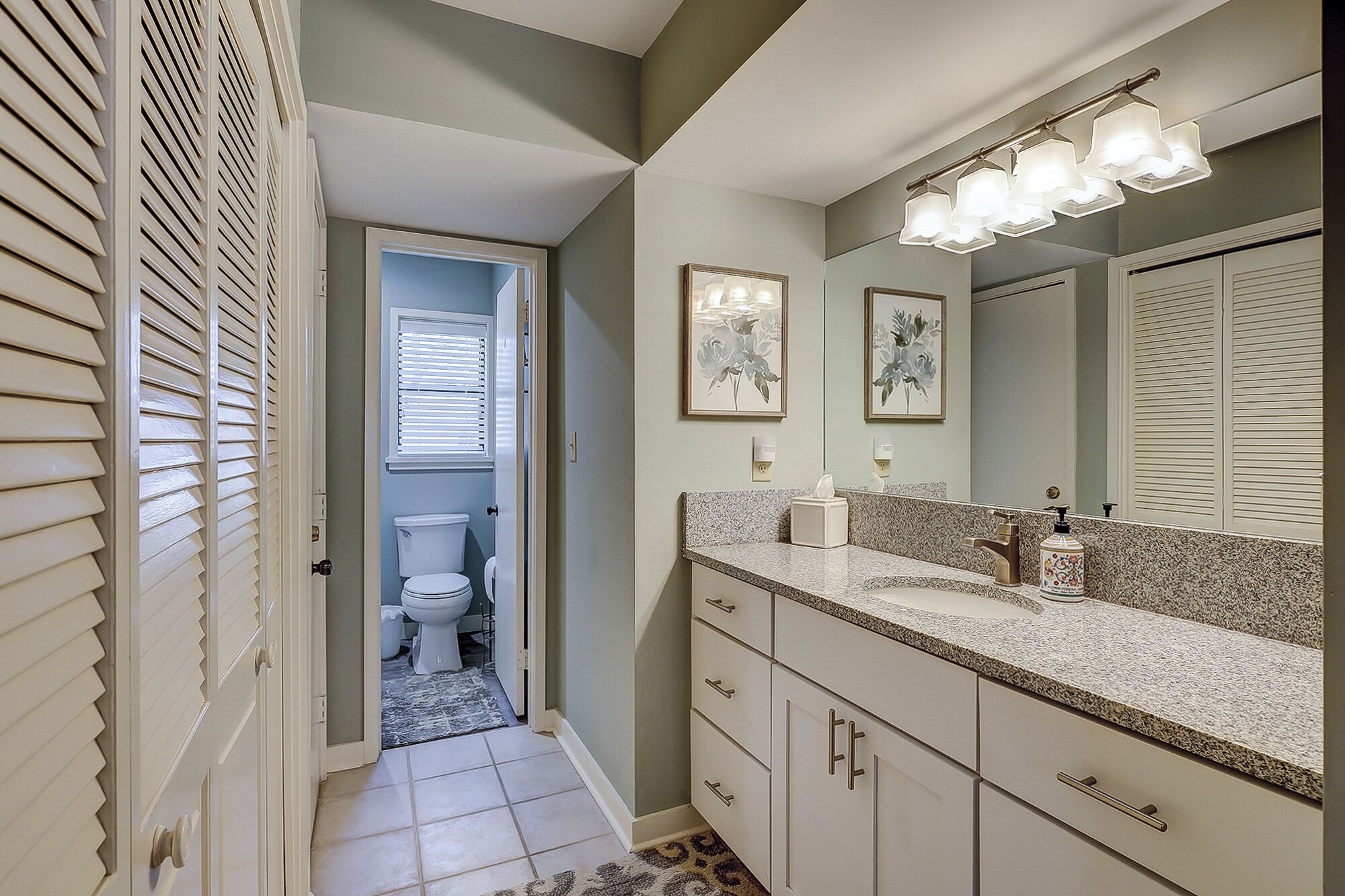 A bathroom with a toilet, sink, and vanity.