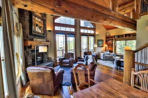 A spacious living area with a fireplace, leather furniture, and large windows.