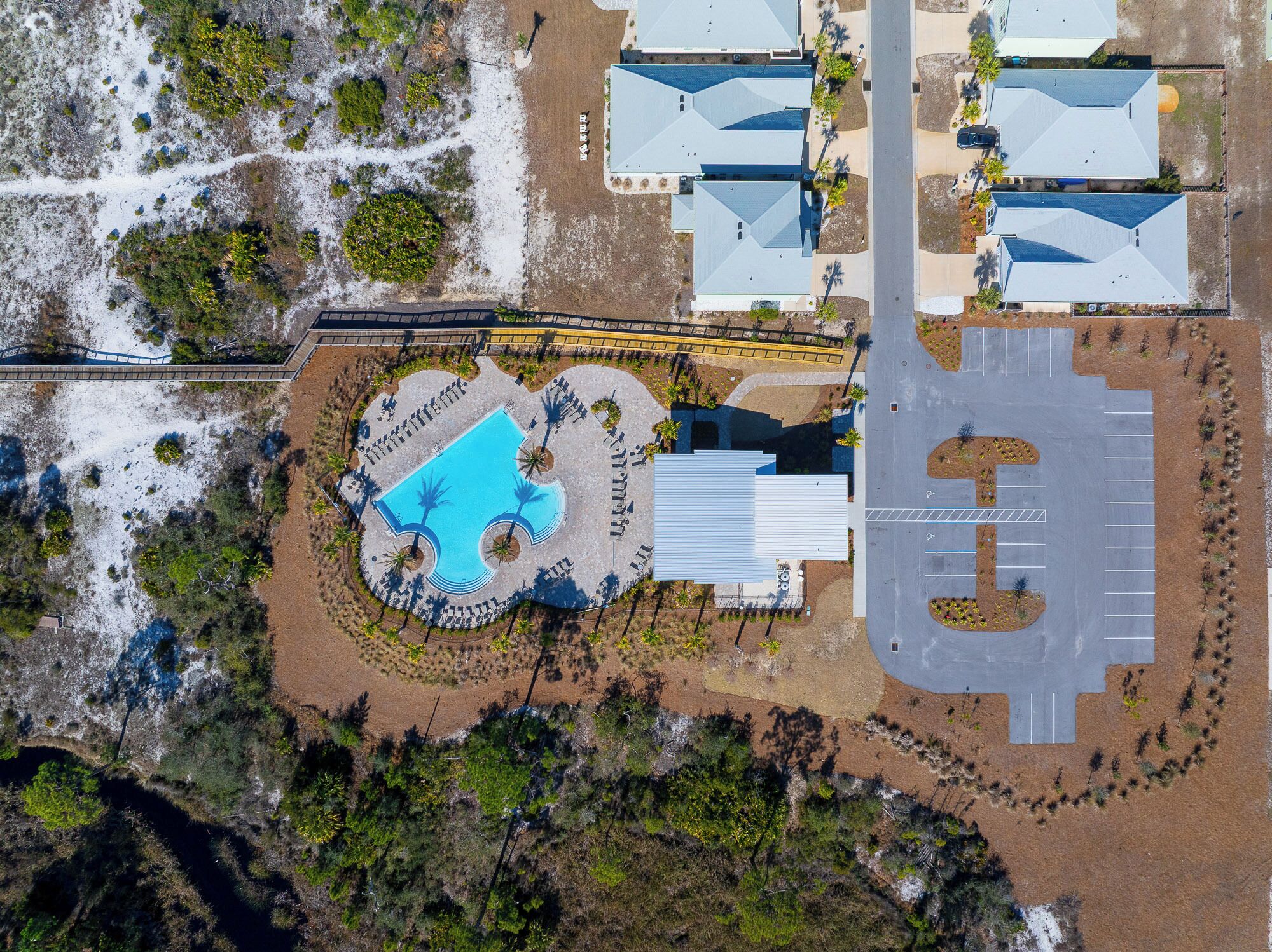 Vue aérienne d’une propriété comprenant une piscine, un parking et plusieurs bâtiments dotés de toits inclinés.