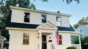 Ein zweistöckiges Haus mit Veranda, Briefkasten und einer US-amerikanischen Flagge.