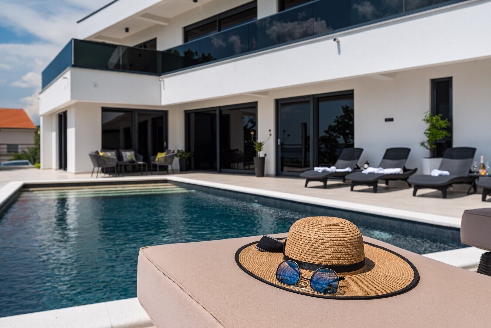 Un espace moderne aménagé au bord de la piscine, avec des chaises longues et un coin repas.