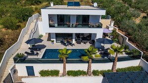 A modern two-story house with a swimming pool, outdoor seating, and a view of the surrounding landscape. - Luxury Villa Spectrum pool 32m2 sauna, family, sea view, bbq (Posedarje)