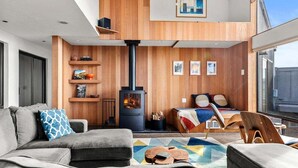 A modern living room with a sofa, a coffee table, and a fireplace. - Moorings | Ocean Views | Hot Tub | Dog Friendly (The Sea Ranch)