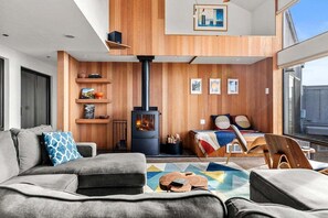 A modern living room with a sofa, a coffee table, and a fireplace. - Moorings | Ocean Views | Hot Tub | Dog Friendly (The Sea Ranch)