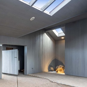 A modern interior with a skylight, concrete walls, and a partially open door leading to another room. - Moorings | Ocean Views | Hot Tub | Dog Friendly (The Sea Ranch)