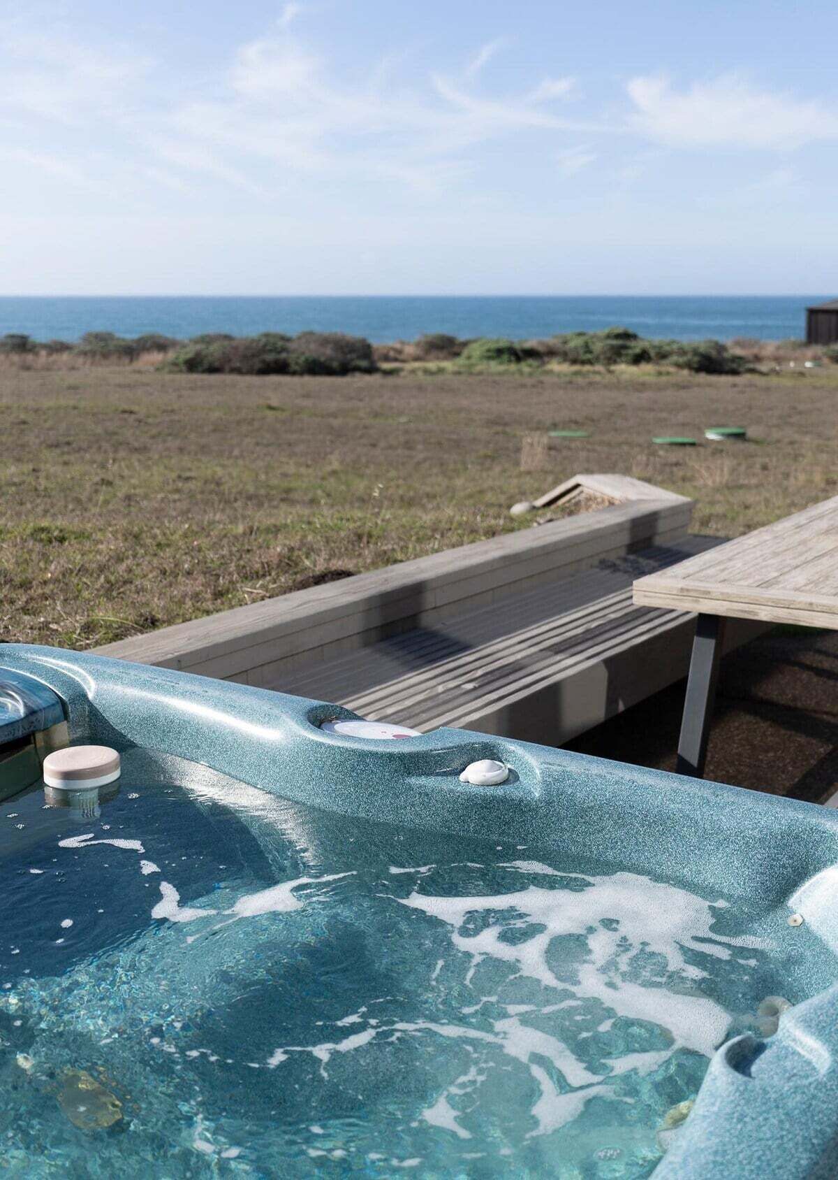 Un jacuzzi con terraza de madera y vista al océano.