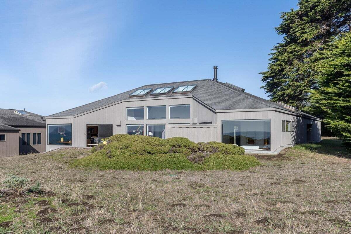 A modern two-story house with a sloped roof, large windows, and a chimney.
