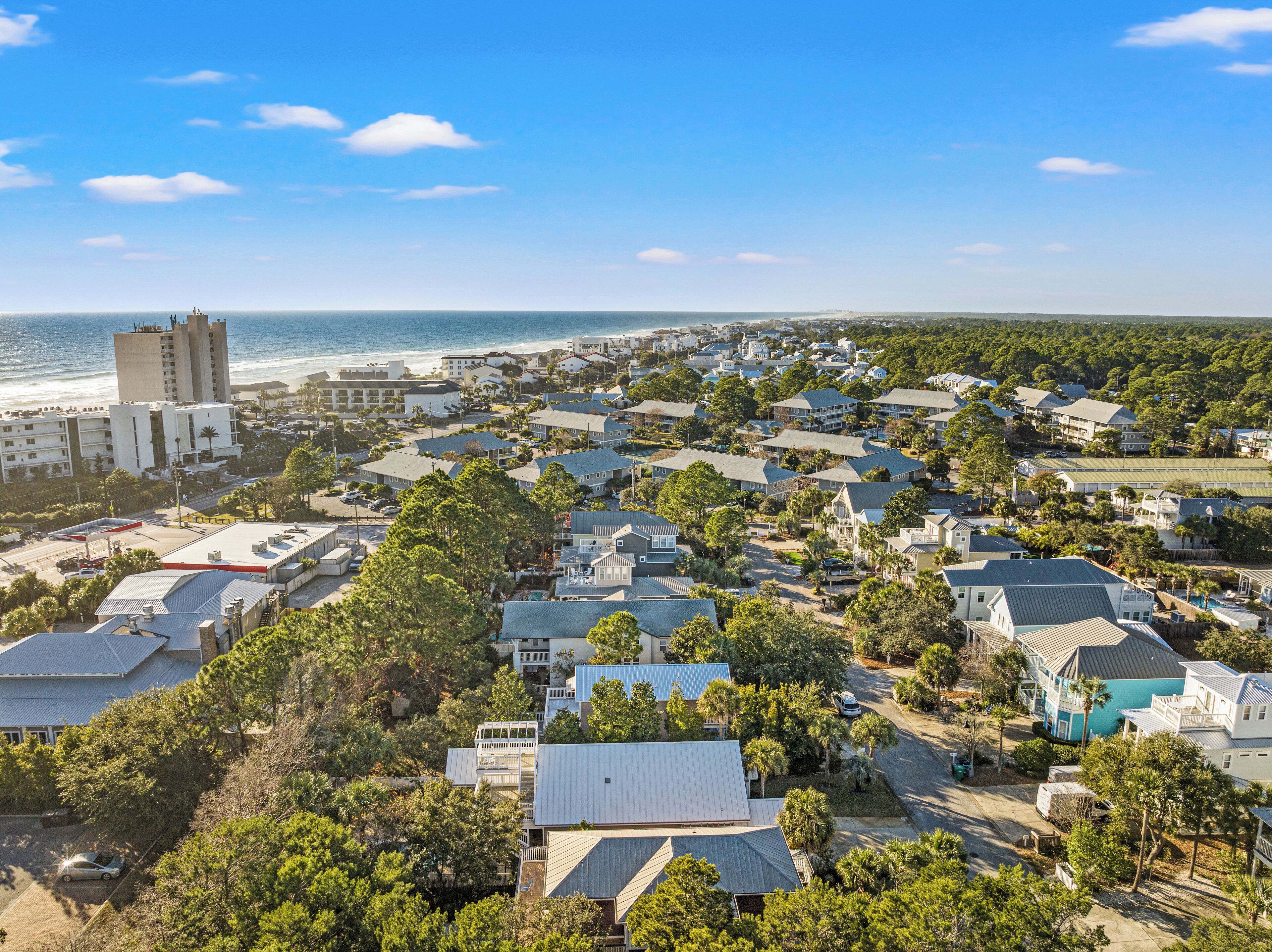 A coastal residential area with a mix of single-family homes and apartment buildings, featuring a prominent lighthouse and beachfront views.