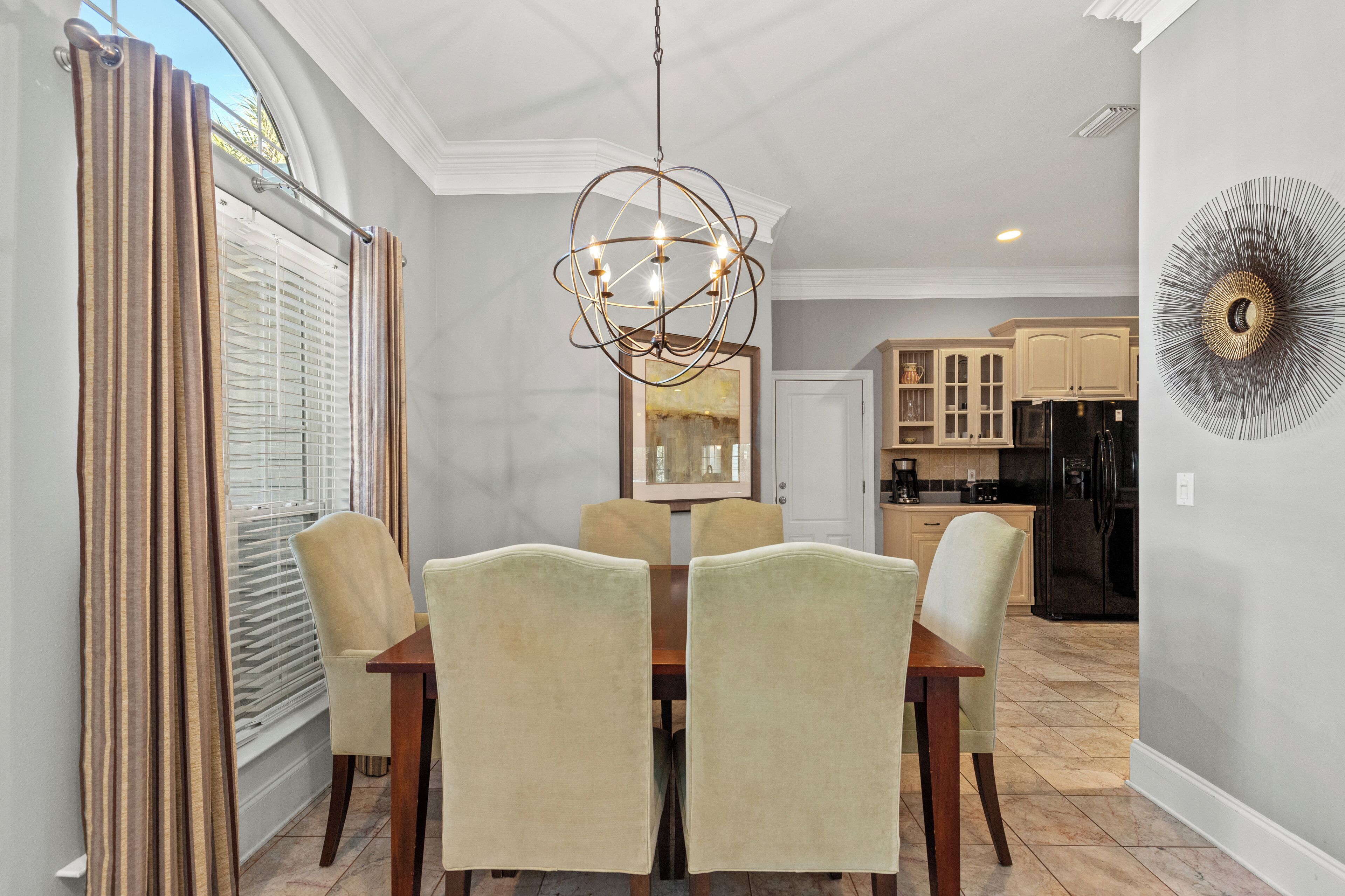 A dining area with a chandelier, a table with chairs, and a view into the kitchen.