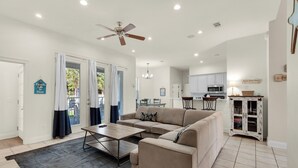 Un vaste espace de vie comprenant un canapé beige, une table basse et un ventilateur de plafond.