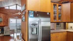 A modern kitchen with stainless steel appliances, wooden cabinetry, and a water dispenser. - Isle Be Back - Soundfront with Pool - 3BR 3BA - Walk to Beach! (Emerald Isle)