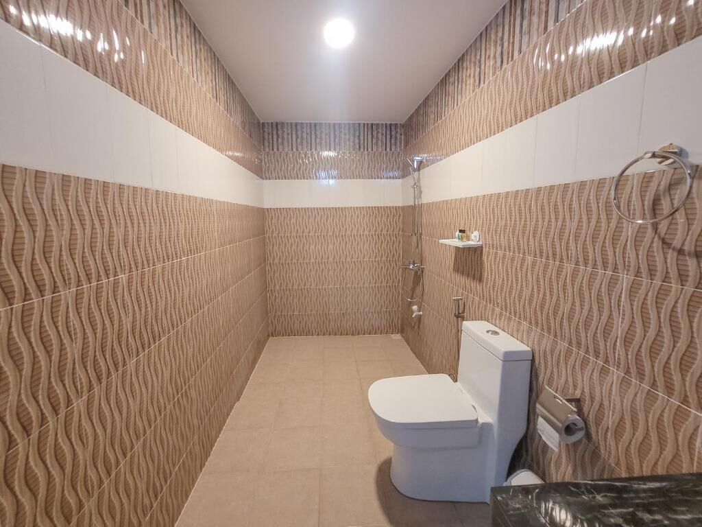 A small, modern bathroom with a textured wall design, a white toilet, and a shower area.
