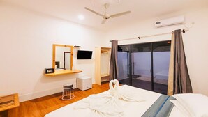 A hotel room with a bed, a desk, a chair, a television, an air conditioner, and a view of the outside. - HI HEAVEN MALDIVES (Thoddoo)
