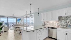 A modern kitchen with white cabinets, a granite countertop, and a dishwasher.