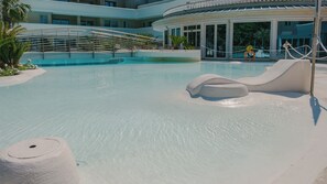 A pool with a slide, lounge chairs, and a building with large windows in the background. - 11 Relais du Lac Charme (Desenzano del Garda)