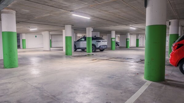 A multi-level parking garage with concrete pillars and a white car parked in one of the bays.