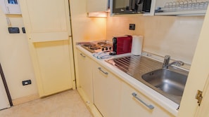 A compact kitchen with a stove, sink, and a microwave above the stove.