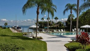 A pool area with lounge chairs, palm trees, and a view of the water. - 3/2 Bay View Condo, Pool, Kayaks (Longboat Key)