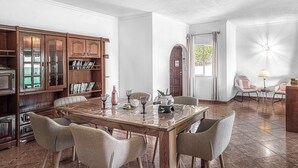 Un coin repas comprenant une table en bois, quatre chaises et une bibliothèque avec des livres et des objets décoratifs.
