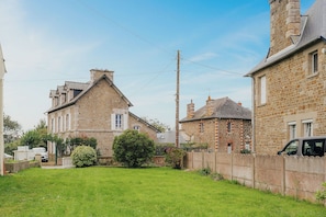 A residential area with stone buildings, a grassy yard, and a parked van.