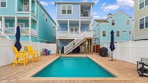 A swimming pool with a wooden deck, surrounded by two-story buildings with balconies and a covered deck area. - Spacious 5BR/5.5BA Beach Home | Private Pool | 120 Steps to Beach | Near Pier (Surfside Beach)