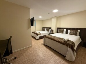 A hotel room with two beds, a flat-screen TV mounted on the wall, and a wooden floor.