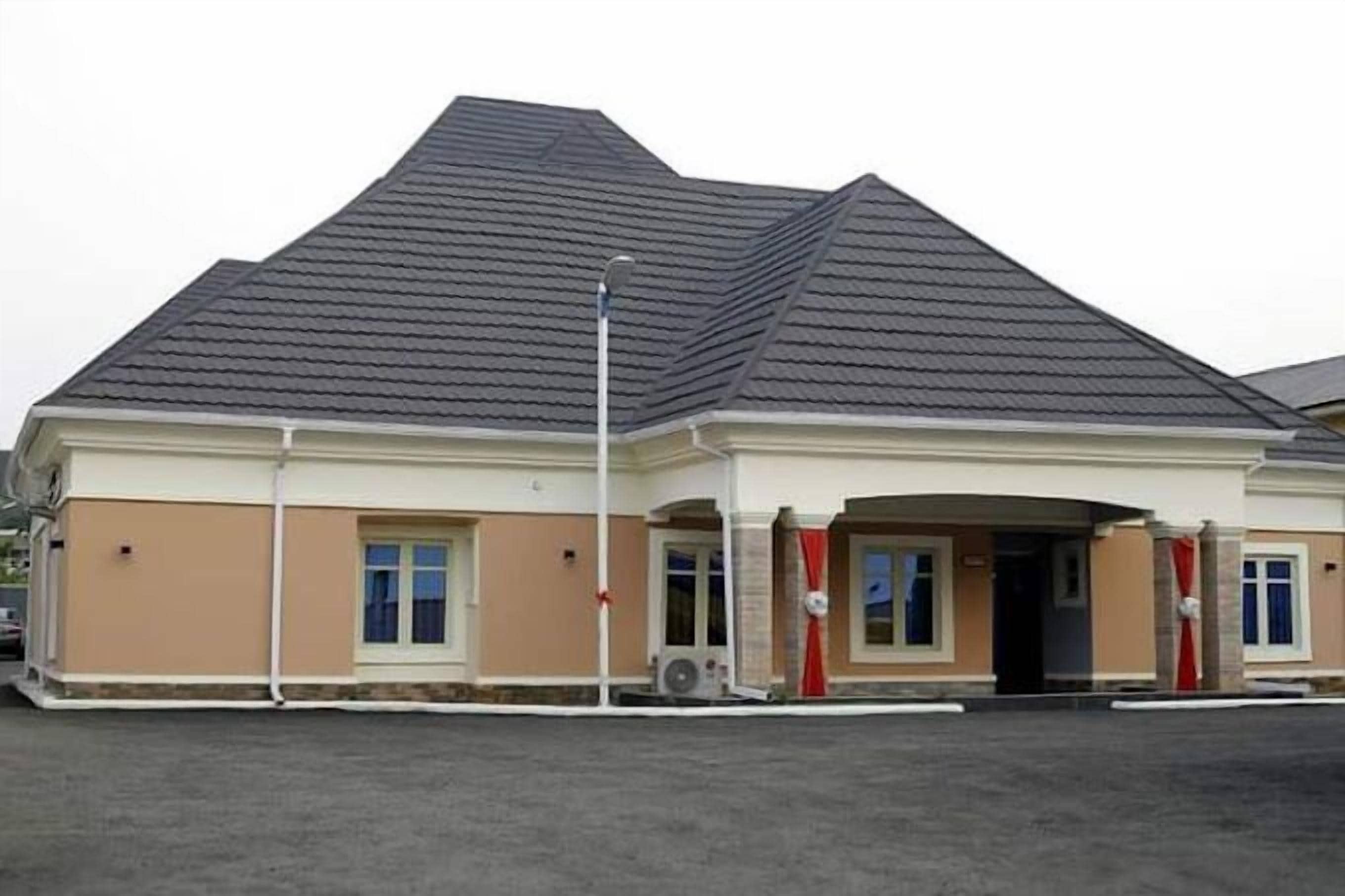 Un bâtiment doté d’un toit en pente, de murs de couleur beige et d’une entrée centrale ornée d’un rideau rouge.