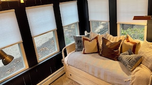 A room with a bed, multiple windows with blinds, a lamp, and a view of the outdoors. - A Step Away: The Retreat – Walk to Town Escape (Saugatuck)