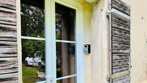 A white door with a glass panel, a wall-mounted doorbell, and a wooden shutter on the right. - Le Moun Mazet 3-star self-catering accomodation, CLIM, Calm, Nature, 6 people, Provence (Miramas)