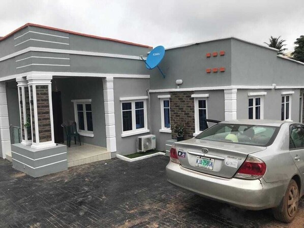A building with a grey facade, white trim, and a satellite dish on the roof. - Readyhomes  Shortlets and Apartments (Ibadan)