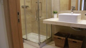 A bathroom with a glass-enclosed shower, a white sink, and two wicker baskets on the floor.