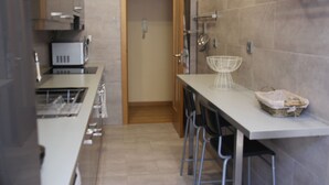 A modern kitchen with a white countertop, stainless steel appliances, and a wooden door.