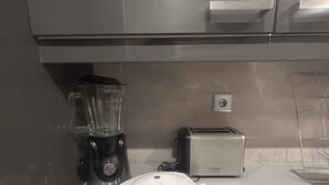 A kitchen with a blender, toaster, and a white toilet seat on the counter.