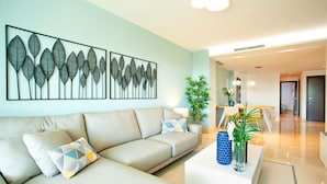 A modern living room with a beige sofa, a coffee table, and a wall-mounted artwork. - Modern Apartment With Pool (Ojén)