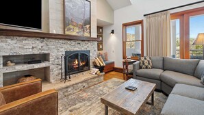 Una sala de estar con chimenea de piedra, un televisor de pantalla plana grande, un sofá y una mesa de centro.