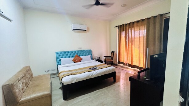 A hotel room with a bed, a chair, a desk, and a television. - Hotel Ashray Noida (Noida)