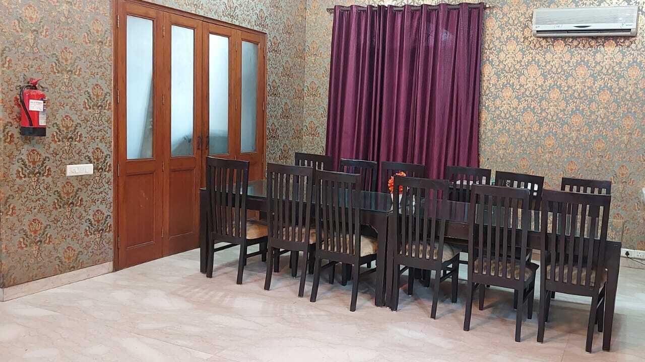 A dining area with a wooden table and chairs, a fire extinguisher, a door, and patterned wallpaper.