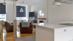 A modern kitchen with white cabinetry, a built-in stove, and pendant lighting.