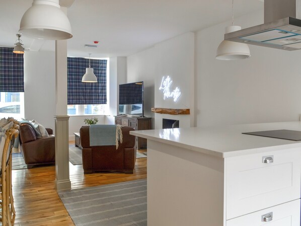 Una cocina moderna con armarios blancos, estufa integrada e iluminación colgante.