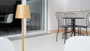 A modern outdoor seating area with a table and chairs, a lamp, and a large umbrella. - Apartment KISTO AT HOME (Bari)