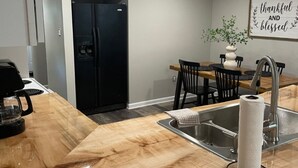 A modern kitchen with a wooden countertop, stainless steel sink, and a black refrigerator.