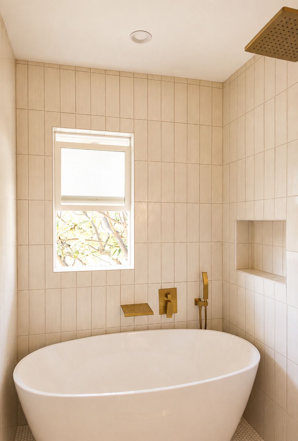 A bathroom with a freestanding bathtub, a window, and a showerhead.