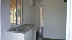 Una cocina estrecha con un lavamanos, estufa y ventana.